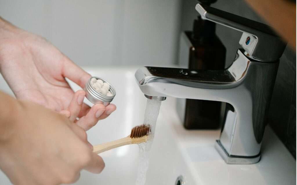 robinet ouvert, avec une personne qui prépare sa brosse à dent