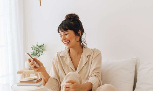 femme en pyjama souriante sur son téléphone avec applications écogestes